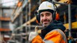 © HendraGalus - Middle Eastern worker wearing safety hardhat and hearing protection at construction site, smiling and giving thumbs up, promoting safe behavior and positivity in workplace to eliminate risk