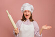 © Андрей Журавлев - Enthusiastic female chef on studio pink background. Portrait of a female person in chef's clothing