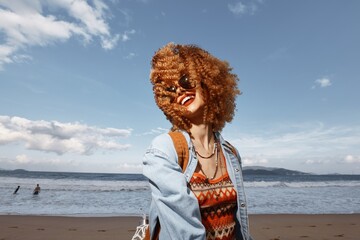 Sticker - Smiling Woman with Backpack Enjoying a Beach Vacation, Experiencing Freedom and Joy under the Blue Sky