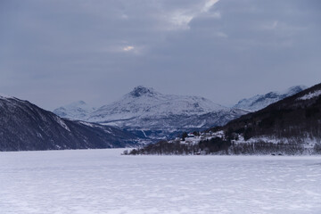 Wall Mural - mountains, a lake and trees covered with snow and clouds