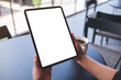 © Farknot Architect - Mockup image of a woman holding digital tablet with blank white desktop screen in cafe