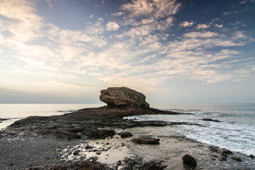 Sunrise with a sea view on a rocky coast in warm colors. Landscape with a lava stone beach at Tarajalejo on Fuerteventura, Canary Islands, Spain.