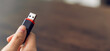 © Chayjitti - Hand holding usb flash drive with connecting to laptop at wooden table