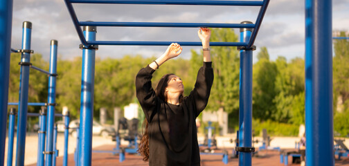Woman Doing sport Pull-Ups on Monkey Bars at Outdoor Gym