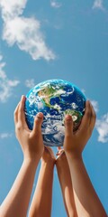 Family hands cupping the Earth globe resting in the middle of their hands, against a light blue sky background