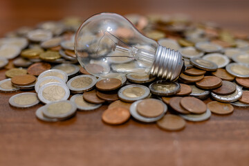 Wall Mural - Lamp among coins. Rising electricity prices and blackout in Ukraine due to war