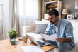 © Srdjan - Young business man small startup company owner, working at home, checking the finances on graphs and laptop. Innovative young freelance male calculating costs and expenses of new product strategy.
