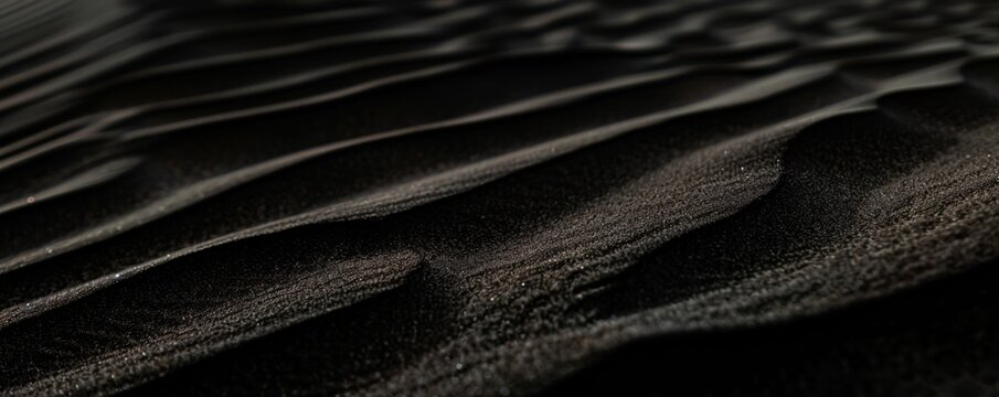 Desert sand. Close-up view of desert sand with subtle black hues color, showing delicate ripples and textures. The soft lighting accentuates intricate patterns, creating a serene captivating scene