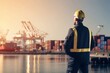 © alisaaa - Shipping, freight and logistics with a supervisor standing on the dock in a harbor, looking at the view and waiting for a delivery or shipment. Safety and control in the import and export industry