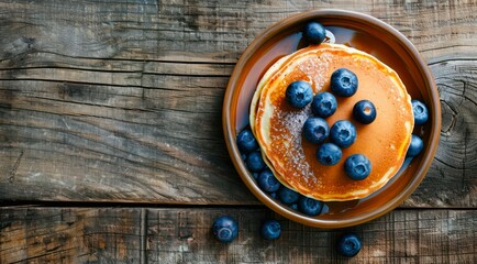 Canvas Print - Plate of pancakes with fresh blueberries on a wooden table, top view.