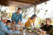 © GR/peopleimages.com - Big family, eating and lunch with food outdoor on patio with conversation, bonding or healthy meal in summer. Parents, grandparents and kids at dining table in home backyard for love, talk or dinner
