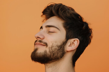 A close up of a man with beard and closed eyes looking to a side