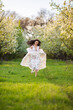 © Michael Rekochinsky - Full-length portrait of a beautiful brunette caucasian woman running in blossoming apple garden in white floral dress on a fresh green grass shot from her face with her hair flying