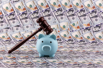 Judge's gavel and piggy bank against a background of 100 US dollar bills