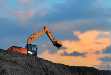 Poster - Coal mining in an open pit. Mining excavator loads coal in haul truck in quarry. Excavator digging in open pit coal mine. Excavator in open-pit on sunset background. Heavy machinery in opencast.