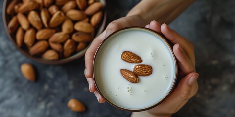 Wall Mural - person holding bowl of almonds and milk on a table top