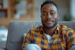 © Irina Mikhailichenko - Handsome young African American man relaxing at home, smiling in in comfortable armchair in modern apartment. Mental health, psychiatrist professional help and support concept image