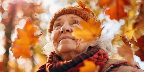 Wall Mural - A woman wearing a hat and scarf is standing in a field of autumn leaves. She is smiling and looking up at the sky