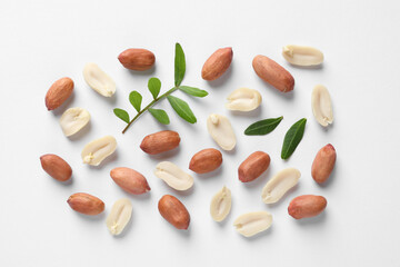 Wall Mural - Fresh peanuts and green leaves on white background, flat lay