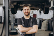 © anatoliycherkas - Smiling bearded mechanic while standing with crossed arms and holding wrenches in a car service