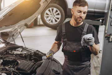 Car mechanic checking the engine oil level in the service center