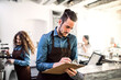 © Halfpoint - Two young baristas working in coffee shop, standing by counter. University students working part-time in cafe.