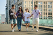 © DragonImages - Friends walking together in an urban area, laughing and talking on a sunny day