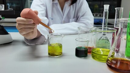Wall Mural - girl scientist loads liquid sample into beaker with plastic pipette. education and science concept