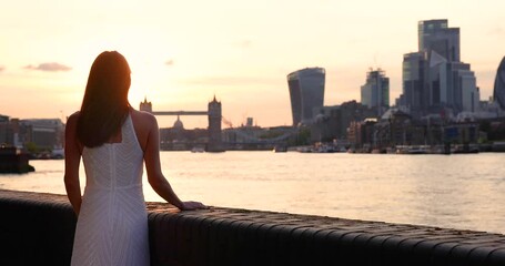 Wall Mural - A happy woman in a white dress enjoys the beautiful summer sunset view of the London skyline