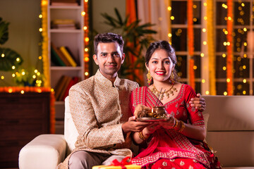 Young Indian asian couple in tradional wear at home celebrating