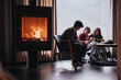 © qunica.com - A warm and intimate scene of friends gathered at home, enjoying each other's company by a glowing fireplace.