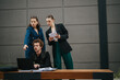 © qunica.com - Group of business colleagues analyzing documents and collaborating on a project while working on a laptop outside in a modern urban setting.