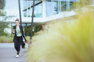 woman employee near business center using phone and walking