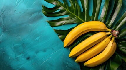 Wall Mural - Ripe yellow bananas on green tropical leaves over bright blue background