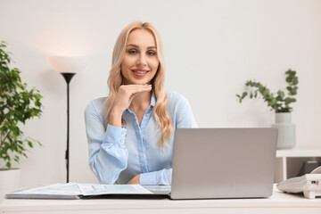 Wall Mural - Happy secretary at table with laptop in office