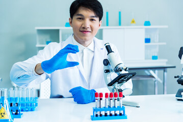 Scientist man look into Microscope research in science laboratory. Asian scientist look at microbiology microscope laboratory equipment chemistry lab. Biochemistry research experiment vaccine concept