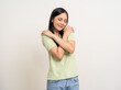© Chanakon - Beautiful smiling happy young asian woman in green shirt. Charming female lady standing pose hugging herself on isolated white background. Asian woman people. Calm peaceful female confident.