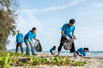 Group teamwork volunteer pick up the plastic bottle on the beach. People male and female Volunteer with garbage bags clean the trash on the beach make the sea beautiful. World environment day CSR.