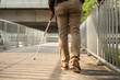 © Chanakon - Young blind man walking in city with walking stick. Visually impaired man difficult to traveling on the road wearing sun glasses Cross the road cross the footbridge