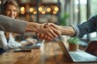 © Vilaysack - Business handshake in modern office setting with colleagues discussing ideas, symbolizing collaboration and successful negotiation.