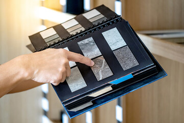 Wall Mural - designer hand pointing at sample stone material texture on furniture finishing catalog in material l