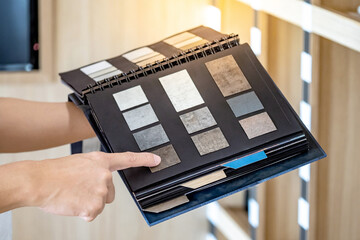 Wall Mural - designer hand pointing at sample stone material texture on furniture finishing catalog in material l