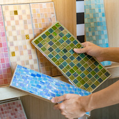 Wall Mural - Architect hand choosing samples of colorful ceramic mosaic tiles in the material library for wall and floor finishing. Compare colorful decoration materials for home bathroom design