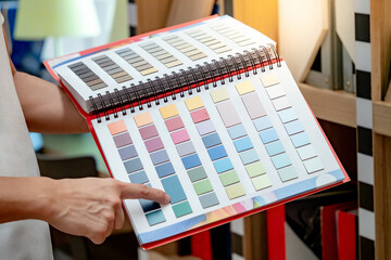 Wall Mural - Designer hand pointing at sample color swatch catalog in material library. Choosing finishing materials for wall and floor interior architecture or furniture design