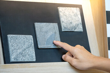 Wall Mural - architect hand choosing and pointing at stone tile material samples on the collection display in the