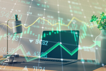 Sticker - Close up of office desktop with laptop and growing green forex chart and arrows on blurry background. Index, finance and market growth concept. Double exposure.