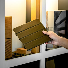 Wall Mural - architect hand choosing and picking outdoor synthetic wood flooring sample from display shelf in mat