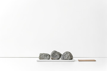 Poster - Three gray rocks on a white platform