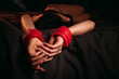 © alexkoral - female hands in red leather BDSM handcuffs for submission and domination sex on a black sheet. Submissive sexy woman slave girl in lingerie lying on the bed in the bedroom