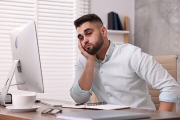 Wall Mural - Overwhelmed man sitting at table in office